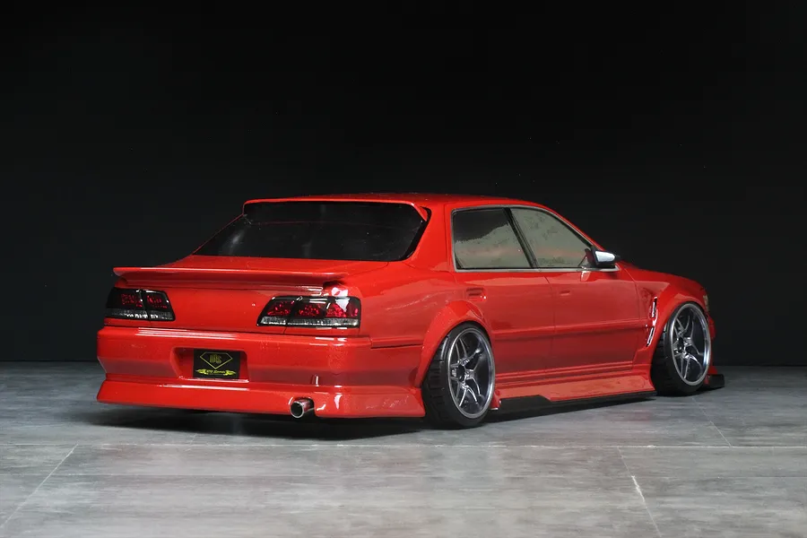 Rear-three-quarter view of a red Pandora RC Toyota Cresta JZX100 drift body shell on a chassis, displayed against a dark studio background.