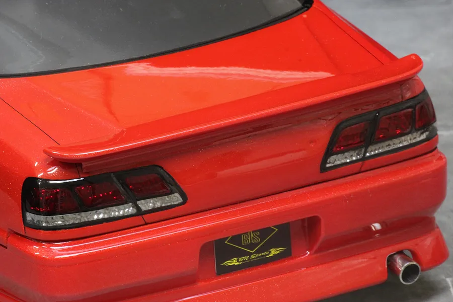Close-up view of the rear of a red Toyota Cresta JZX100 RC drift car body showing tail lights, spoiler, and exhaust tip.