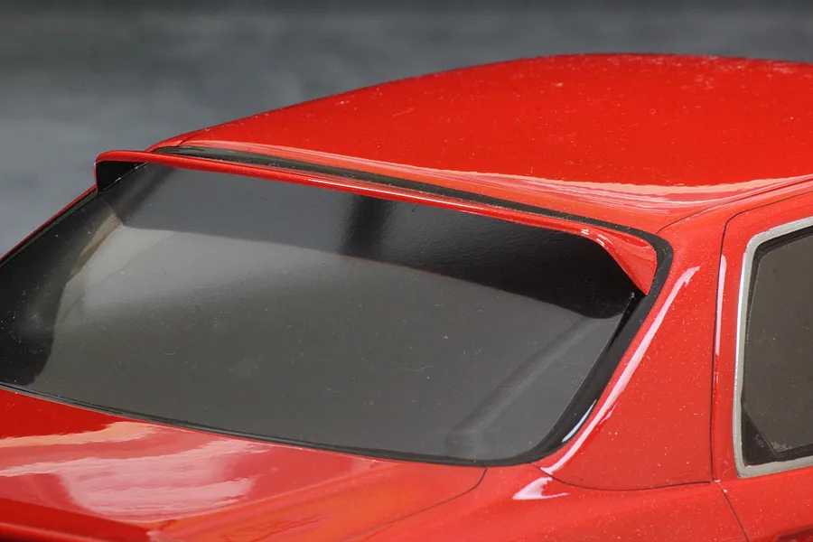 Close-up of the rear window and roof section of a red RC drift car body shell, showing a mounted roof spoiler.