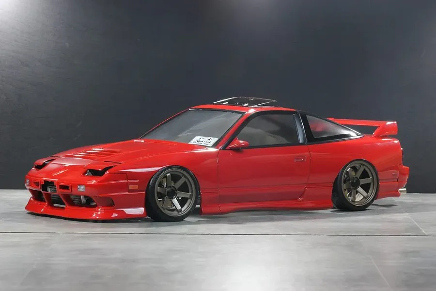 Painted red Pandora RC Nissan 180SX Kouki body shell mounted on an RC drift car chassis against a dark background.