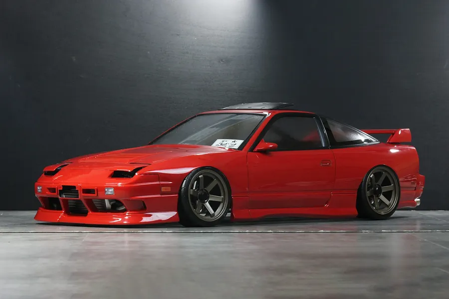 Studio photo of a red Pandora RC RPS13 180SX Kouki drift body shell mounted on an RC chassis against a dark background.