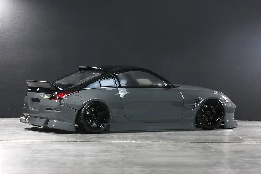 Side-rear view of a grey Pandora RC 350Z drift car body shell with black wheels, roof spoiler, and exhaust tip.
