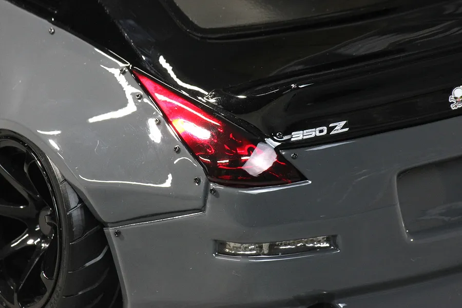Close-up rear quarter view of a grey and black RC drift car body showing the tail light, 350Z badge, and wide fender flare.
