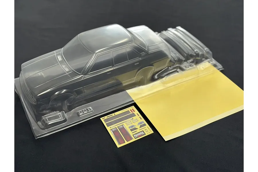 Pandora RC Toyota Corolla KE70 clear unpainted RC body shell with included decal sheet and window masks on a dark surface.