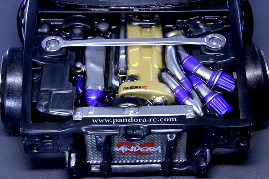 Detailed scale model RC car engine bay installed in a chassis with a gold valve cover and Pandora RC branding.
