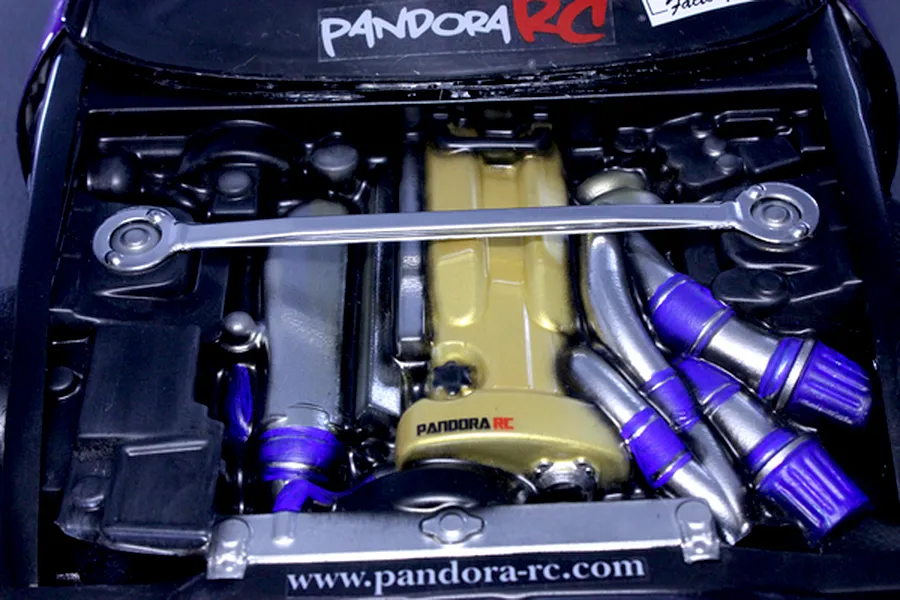 Detailed top-down view of a Pandora RC scale model engine bay with gold valve cover, strut bar, and intake details.
