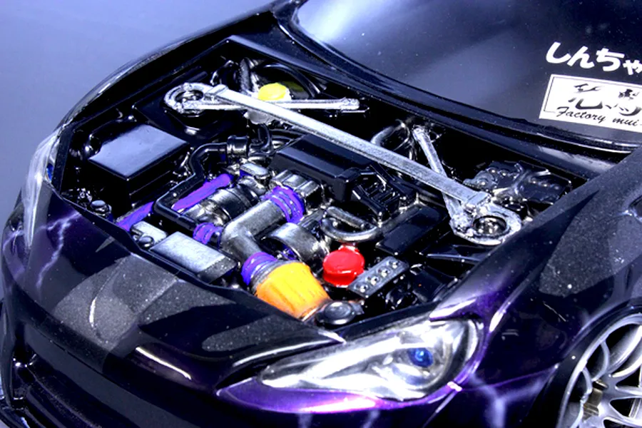 Detailed scale model engine bay installed inside a dark purple RC car body with a strut bar.