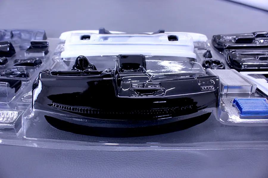 Uncut plastic RC interior parts set including dashboard and accessories in a clear blister pack.