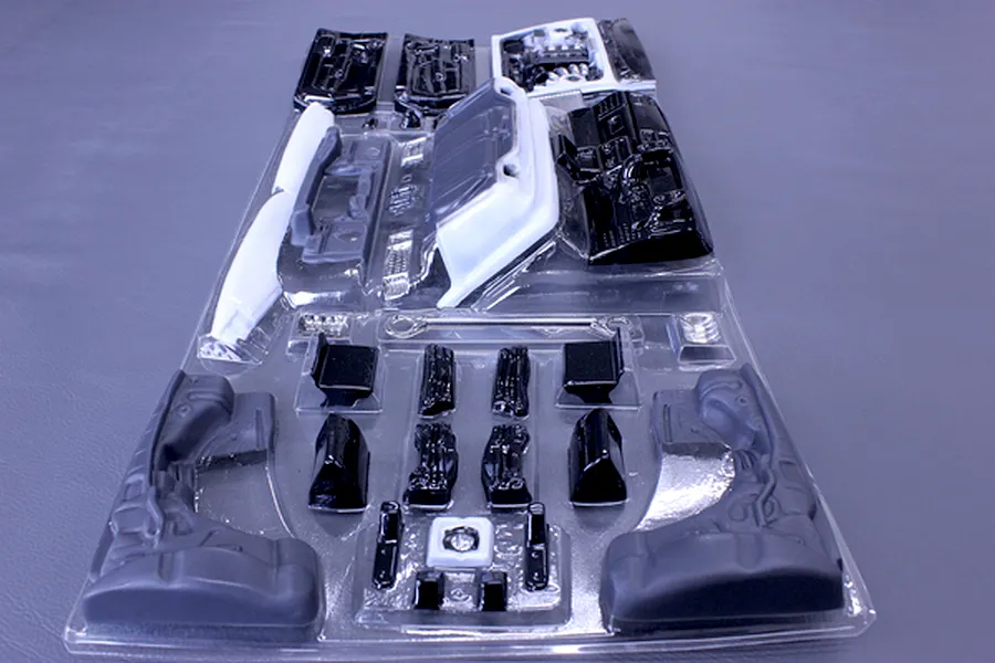 Unpainted RC car interior and accessory parts in a clear plastic vacuum-formed blister pack.