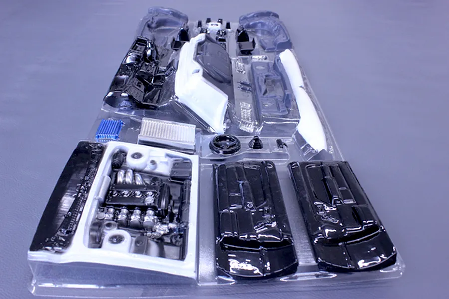 Unpainted plastic RC car interior and engine bay parts set in a clear vacuum-formed packaging tray.