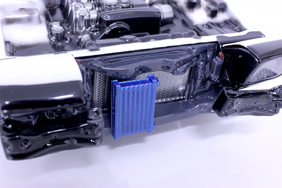 Close-up of a painted RC car interior detail set featuring an engine bay and a blue intercooler mounted in the front.
