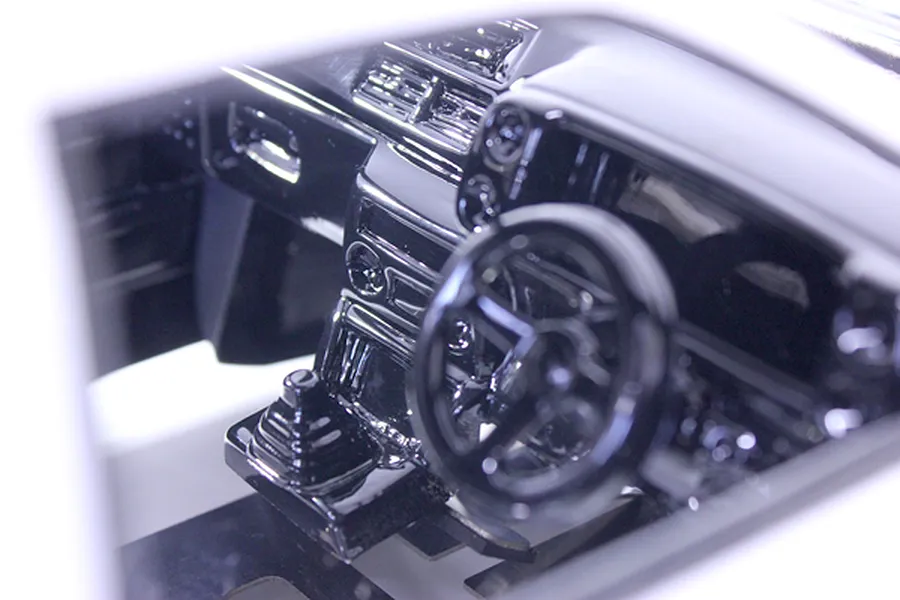 Close-up of a detailed black RC car interior set installed in a model body, showing the dashboard and steering wheel.