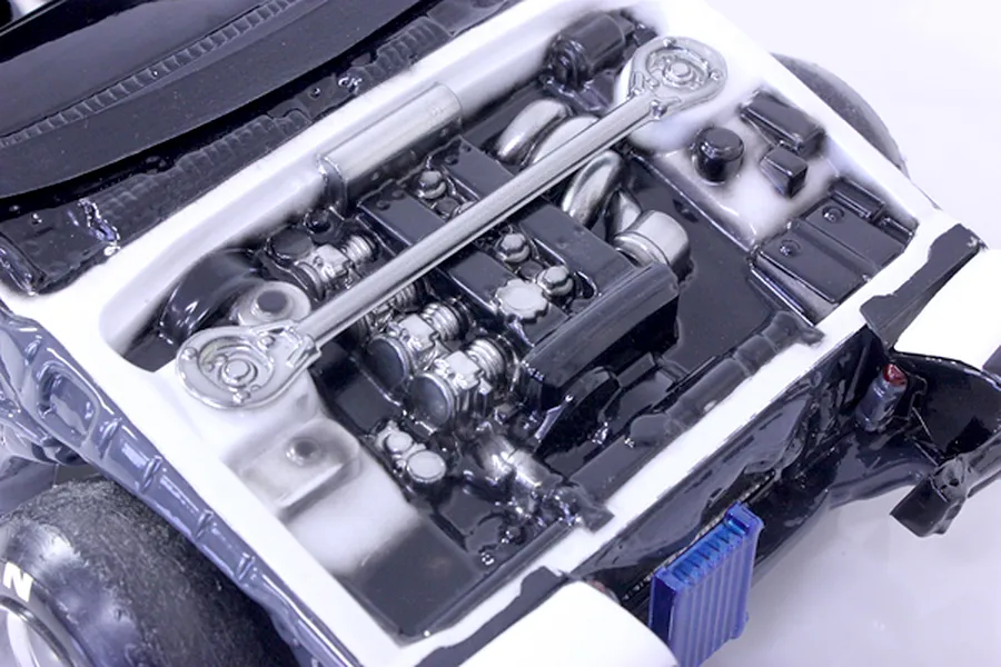 Close-up view of a detailed model car engine bay accessory set installed in a chassis.