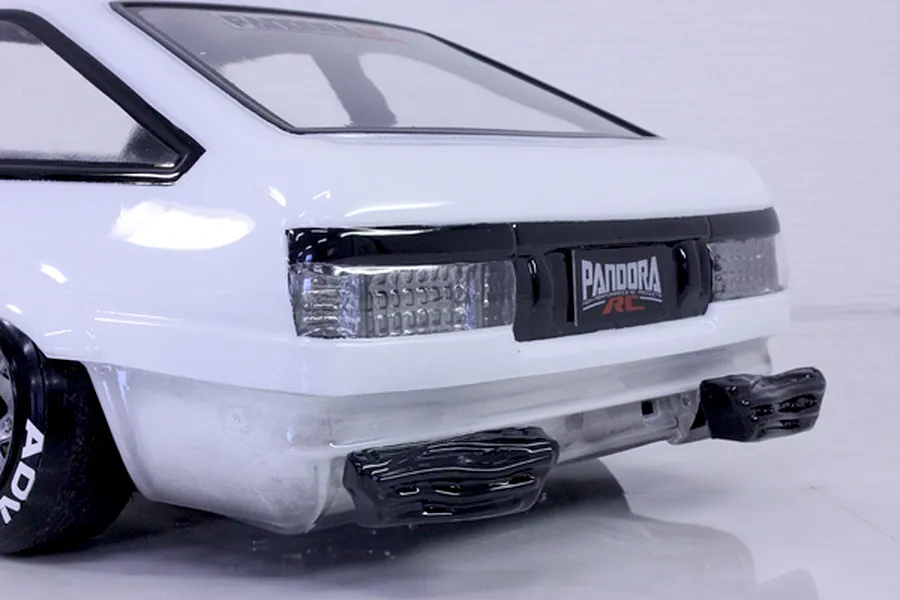 Close-up of the rear end of a white RC car body showing detailed tail lights and custom bumper inserts against a white studio background.