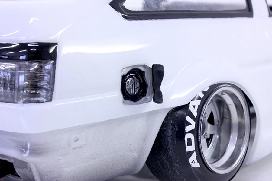 Close-up view of a white RC drift car body showing rear wheel, tire with Advan lettering, tail light, and fuel filler cap detail.