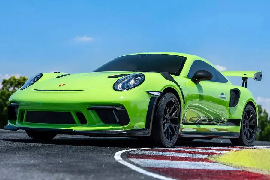Kyosho Fazer Mk2 2018 Porsche 911 GT3 RS RC car in lizard green driving on an outdoor track against a blue sky.