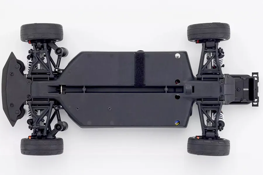 Top down view of the black plastic chassis of the Kyosho Fazer Mk2 RC car featuring suspension arms, wheels, and battery strap.