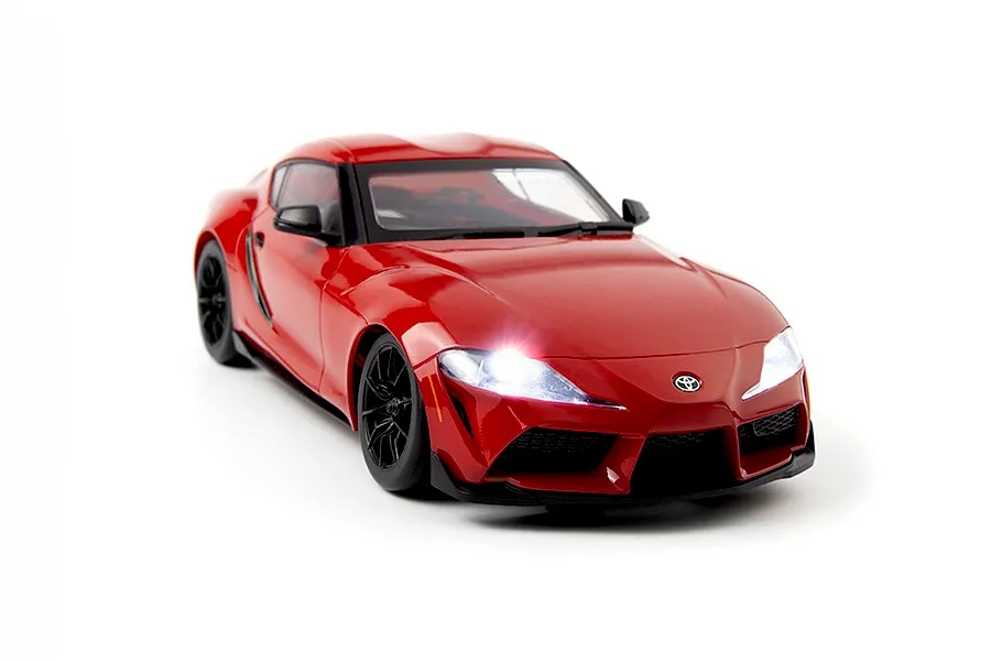 Studio product photo of the HPI Stage D24 Toyota Supra GR RC car in red with glowing headlights against a white background.