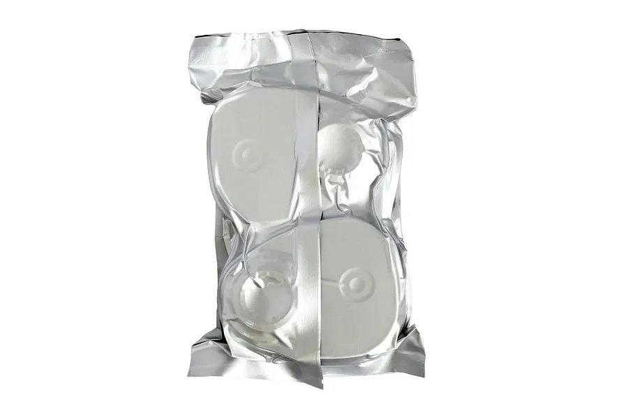 Sealed silver foil packaging containing a pair of white organic vapour filters against a plain white background.