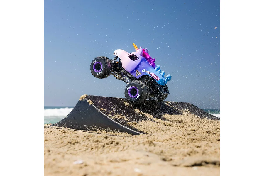 Sparkle Smash monster truck RC car jumping off a sand ramp at the beach under a clear blue sky