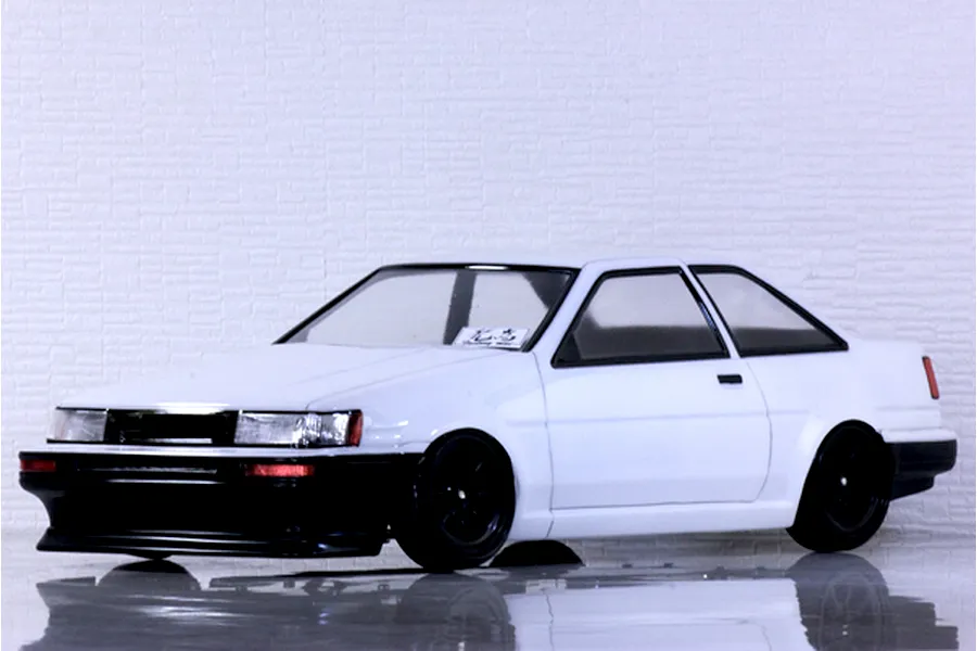 Studio shot of a white Pandora RC Toyota AE86 Corolla Levin 2DR scale model car with black wheels.