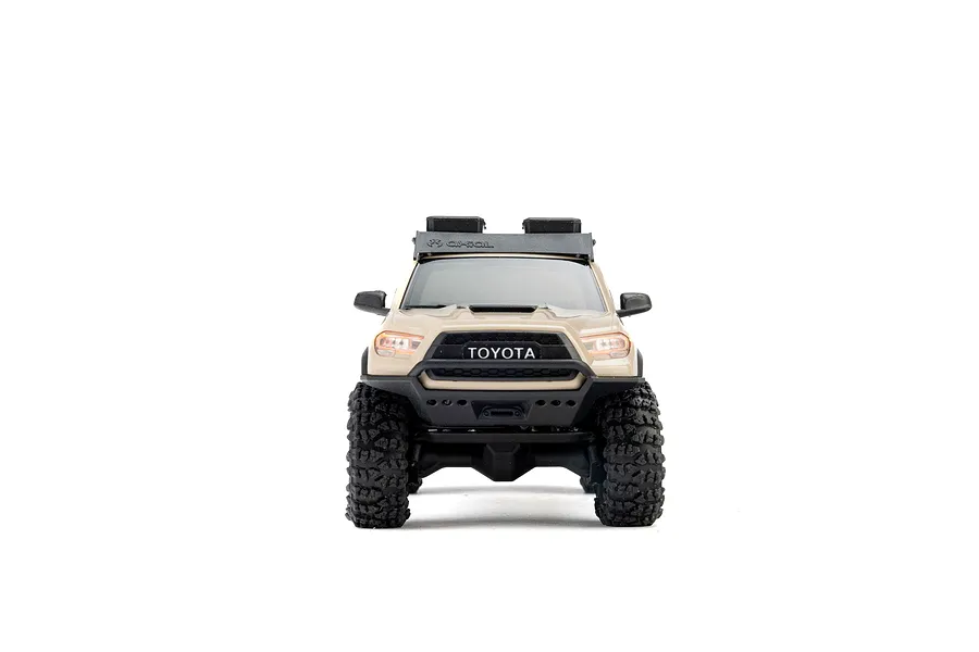 Front view of the Axial SCX30 Toyota Tacoma RC rock crawler in brown, featuring a roof rack and chunky off-road tires against a white background.