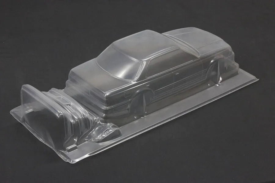 Unpainted clear polycarbonate RC drift car body shell sitting on a dark surface, showing the sedan profile.