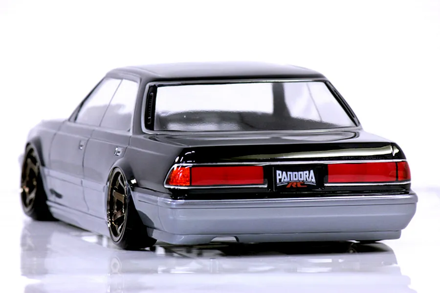Rear three-quarter view of a painted black and silver RC drift car body shell with Pandora RC branding on the license plate, set against a plain white background.