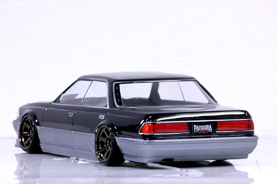 Rear-three-quarter view of a black and silver RC drift car body on a white studio surface.