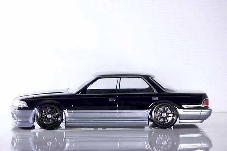 Side profile of a painted black and silver Toyota Mark II RC drift car body shell on a white studio background.