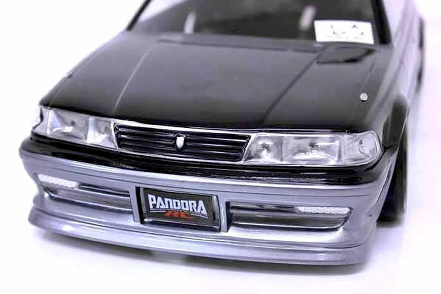 Close-up front view of a black and silver RC drift car body shell with Pandora RC license plate against a white background.