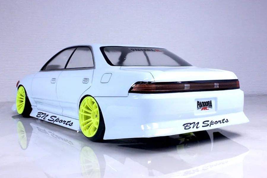 Rear three-quarter view of a painted white Pandora RC Toyota Mark 2 JZX90 body shell featuring bright yellow wheels and BN Sports decals.