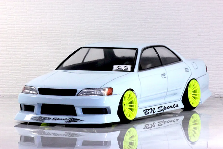 Light blue radio controlled drift car body shell on a reflective surface against a white textured background.