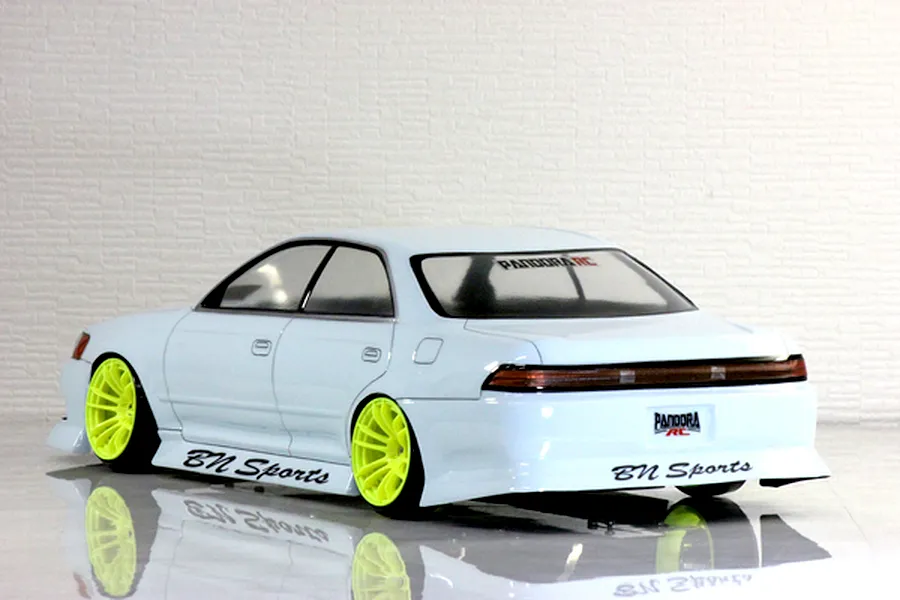Rear three-quarter view of a white Toyota Mark II JZX90 RC drift car body shell with bright yellow wheels and BN Sports decals.