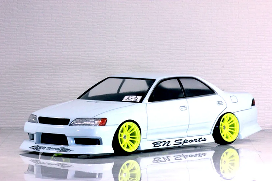 Side-profile view of a white RC drift car body featuring bright fluorescent yellow wheels and BN Sports branding against a textured wall background.