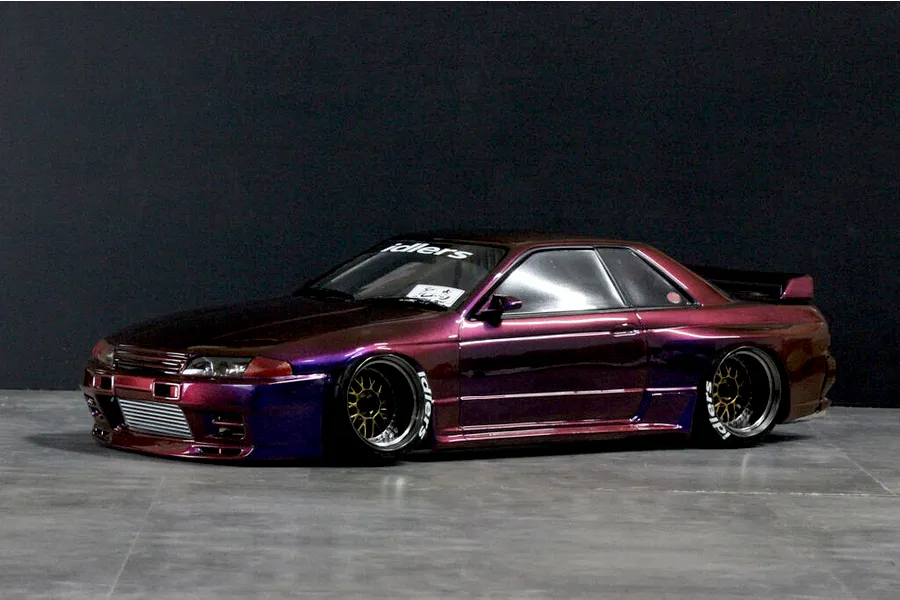 Custom painted purple and bronze RC drift car body modeled after a Nissan Skyline GT-R R32 on a dark studio floor.