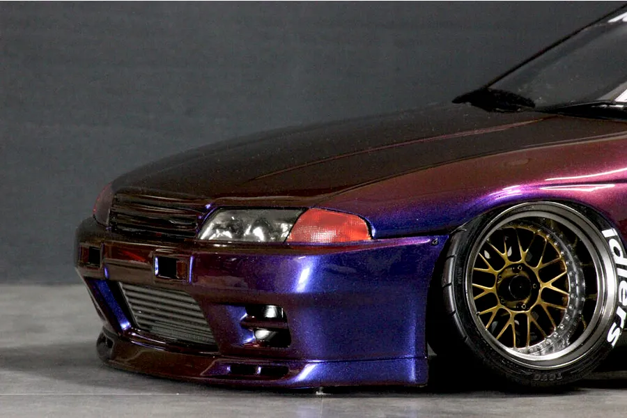 Close-up front quarter view of a custom painted purple and bronze metallic RC drift car body shell mounted on a chassis with custom wheels.