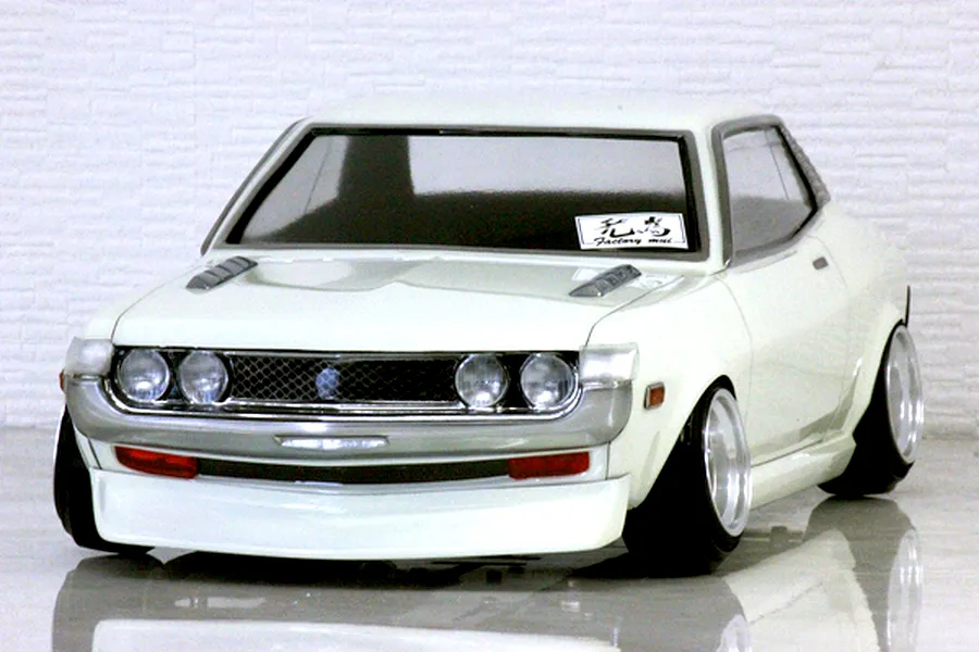 Front three-quarter view of a white Toyota Celica 1600GT RC drift car body shell on a reflective surface.