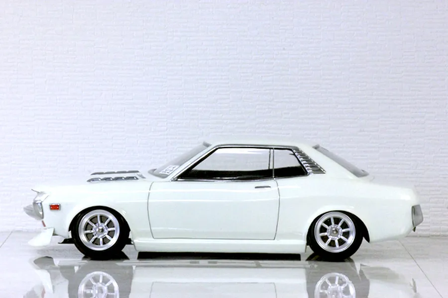 Side profile view of a white Toyota Celica 1600GT RC drift and touring car body shell mounted on a chassis with custom wheels.