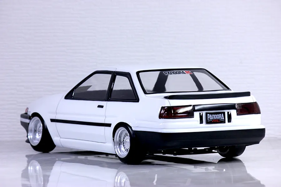 Rear three-quarter view of a white RC drift car body shell modeled after a Toyota AE86 Trueno, featuring custom wheels and black trim.