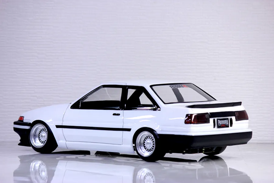 Rear-three-quarter studio view of a white Pandora RC Toyota AE86 Sprinter Trueno 2-door body shell on a glossy surface.