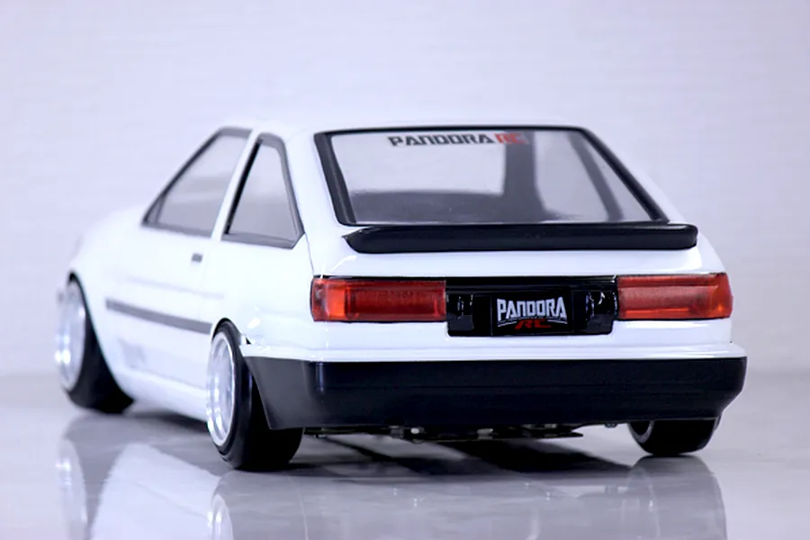 Rear three-quarter view of a white Toyota AE86 Corolla Levin RC drift car body shell on a reflective white studio surface.