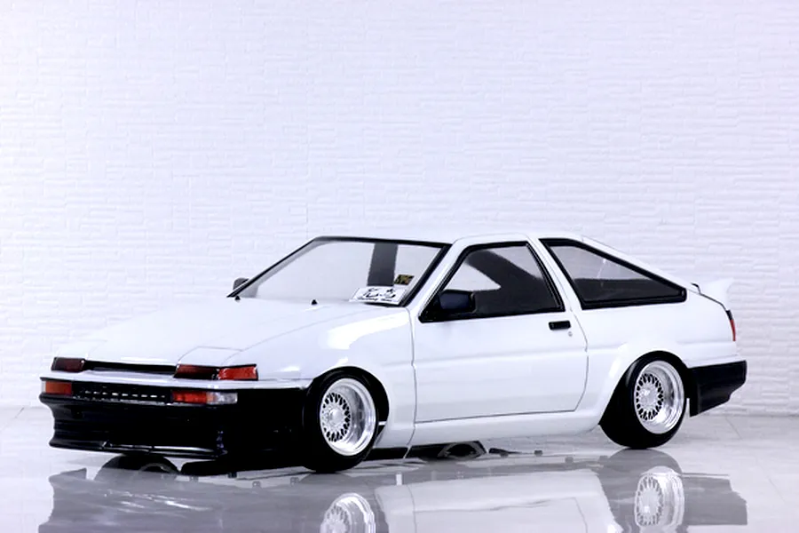 Painted white Toyota AE86 Sprinter Trueno RC drift car body mounted on a chassis with custom mesh wheels.