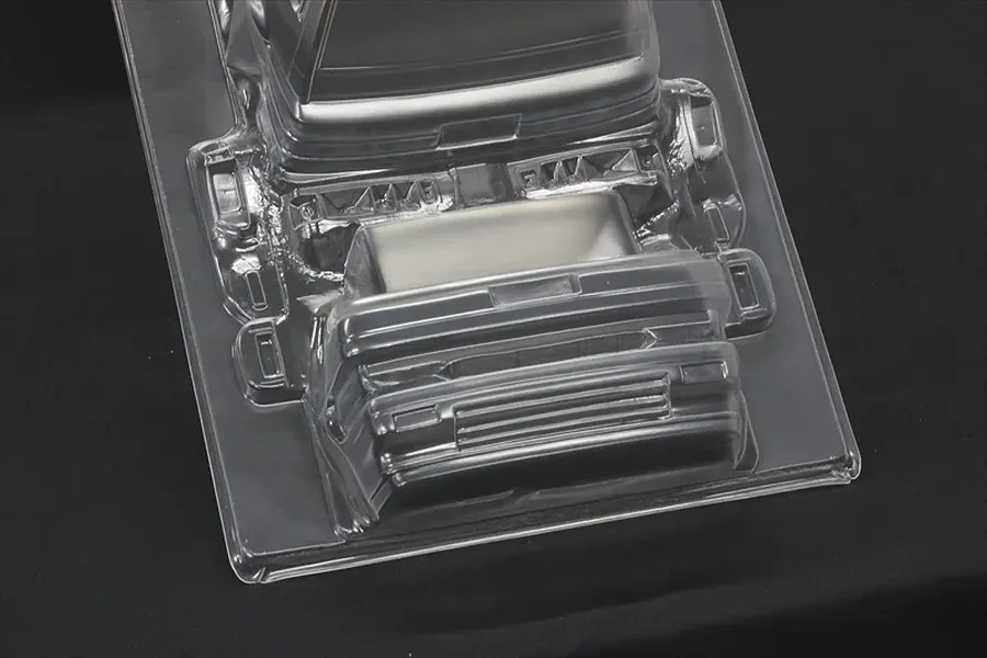 Unpainted clear polycarbonate RC car body accessories including bumpers and separate parts on a black background.