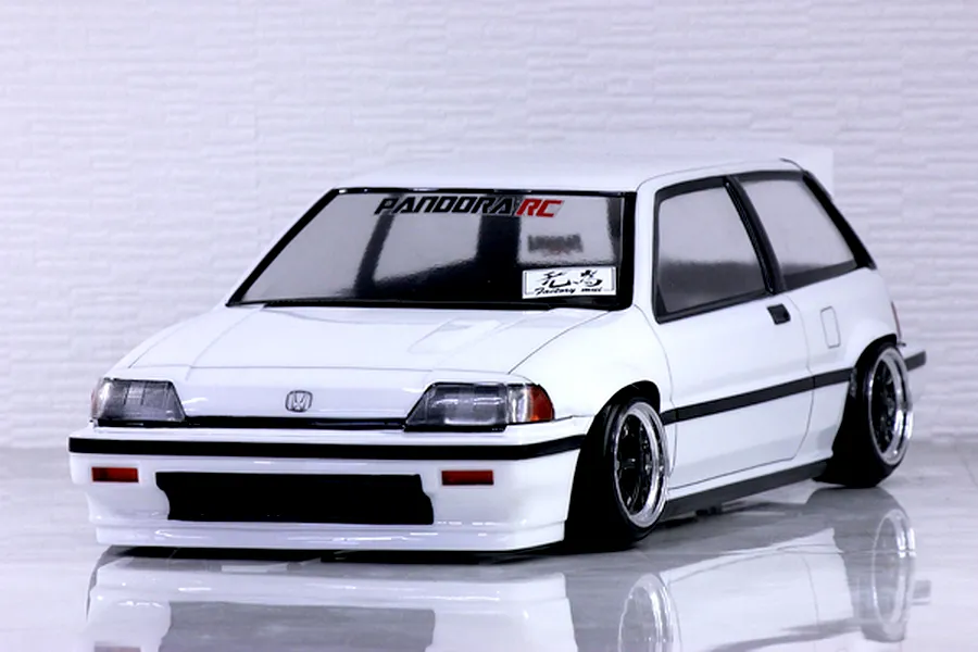 A painted white Pandora RC Honda Civic Si RC drift car body shell mounted on a chassis with custom wheels against a white brick background.