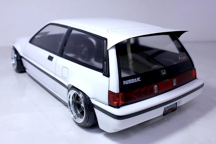 Rear three-quarter view of a white RC car body shell resembling a classic Honda Civic hatchback with custom wheels and decals.
