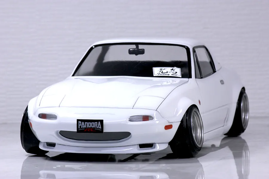 Front three-quarter view of a white Pandora RC Mazda Eunos Roadster NA RC drift car body shell on a reflective surface.