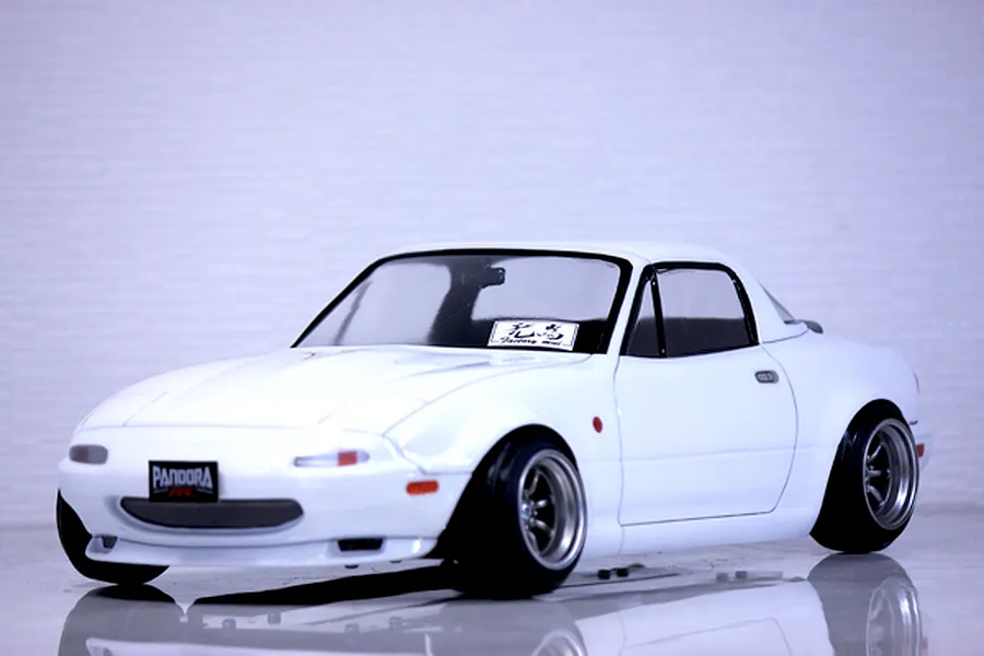 Studio shot of a white Pandora RC Mazda Eunos Roadster body shell mounted on an RC chassis with custom wheels against a light background.