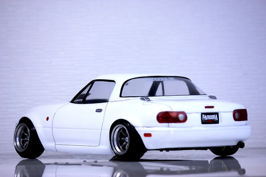 Rear three-quarter view of a white Pandora RC Mazda Eunos Roadster body shell on a reflective surface.