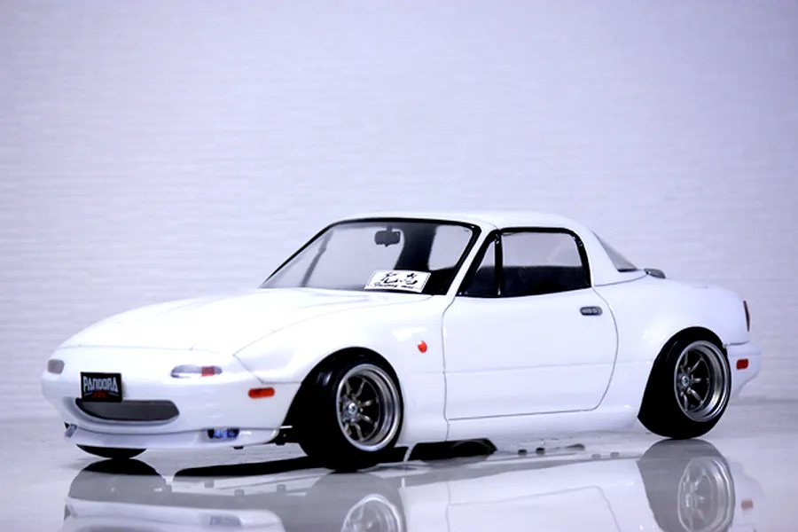 A painted white Mazda Eunos Roadster NA RC body shell mounted on a chassis with custom wheels against a neutral background.